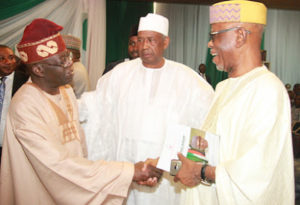 Member Organizing Committee, Mallam Ismaila Isa (m) watched the APC National Leader, Asiwaju Bola Tinubu exchange pleasantries with the APC National Chairman, Chief Odigie Oyegun during the presentation of a book titled Muhammadu Buhari: The Challenges Of Leadership In Nigeria authored by Prof. John Paden at the African Hall, International Conference Centre, Abuja.